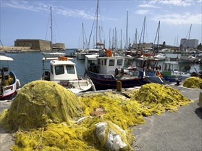 In the foreground yellow fishing nets of local Greek fishermen behind them several small fishing
