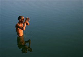 Hindu man worshipping the sun god in the Gandaki river, Nepal, Asia