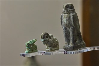 Antique statuettes in green and grey depicting various figures and animals, falcon, wild goat,