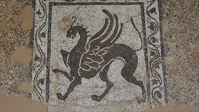 Antique mosaic with a winged mythological horse surrounded by decorative patterns, outdoor area,