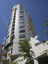 A modern high-rise building with balconies and colourful elements under a clear blue sky, Lisbon,