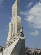Large monument with many figures looking up towards a figure, blue sky, Lisbon, Portugal, Europe
