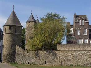 Old city wall with round towers, flanked by older and modern buildings, Maastricht, Netherlands