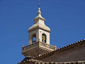Bell tower of a historic church building with bell under a clear blue sky, palma de Majorca with