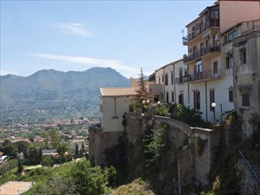 City on a hill with mediterranean houses and old city walls in front of a mountain landscape in