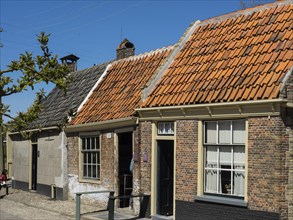 Traditional brick houses with red roofs in a sunny street, Enkhuizen, Nirderlande