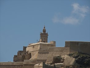 A historic fortress with a striking tower and several levels of sandstone, the island of Gozo with