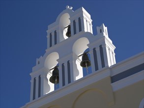 White bell tower of a church in front of a blue sky in Greece, The volcanic island of Santorini