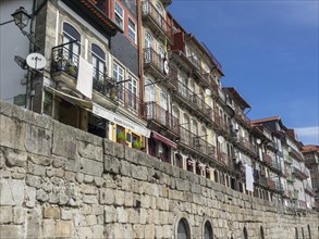 Row of houses with balconies and colourful facades in front of an old stone wall, The old town of