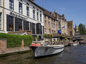 A hotel with a boat on a river, surrounded by historic buildings on a sunny day, historic city on