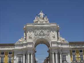 Triumphal arch with decorative statues and ornaments against a clear blue sky in Lisbon, Lisbon,