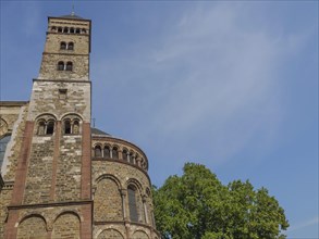 Detailed view of a historic church tower with stone walls and greenery below, under a clear blue