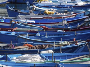 Harbour with numerous densely stacked blue wooden fishing boats floating on the water, The city of