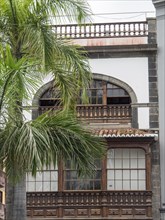 Three-storey historic building with palm trees and wooden balcony, Lanzarote, Spain, Europe