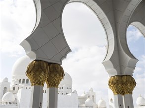 White arches with golden accents against a backdrop of magnificent architecture and blue skies, Abu