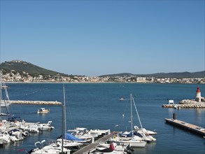 A harbour with many parked yachts and boats, blue water and a town in the background, la seyne sur