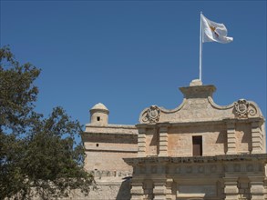 An old castle with a flag and a tower in the foreground, bright blue sky, historic buildings with