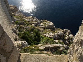 Rocky coast sloping into the sunny sea, the old town of Dubrovnik with historic houses, churches,