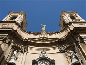 View of a baroque church facade with statues under a clear blue sky, Valetta, Malta, Europe