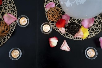 Table decoration with candles, wicker balls and rose petals