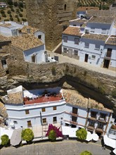 Close-up of houses integrated between rock walls with a terrace and flowering plants in the