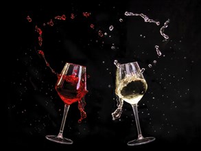Two wine glasses, one with red wine and the other with white wine, splash dynamically against a