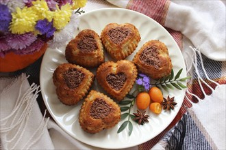 Heart-shaped cookies with chocolate shavings arranged on a plate with flowers, kumquats, and star
