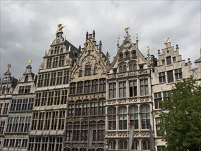 A row of ornate historic buildings with Renaissance and Baroque elements under a cloudy sky,
