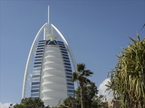 The Burj Al Arab Hotel in Dubai with palm trees and green spaces in the foreground, dubai, arab