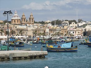 Coastal town with harbour, many fishing boats and a striking church in the centre, Valetta, Malta,