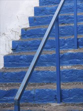Close-up of a blue stone staircase with metal railing and white background, The volcanic island of