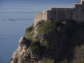 Historic fortress on the coast overlooking the calm sea and overgrown cliffs, the old town of