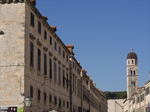 Long row of buildings with bell tower in the background under blue sky, the old town of Dubrovnik