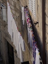 White linen and colourful clothes hanging on a line in front of an old stone house, the old town of