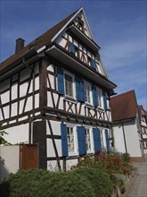 Half-timbered house with blue shutters under a clear blue sky, looks summery, historic