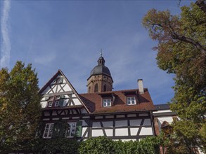 Half-timbered house and church with bell tower in clear autumn weather, historic half-timbered