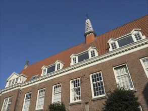 Brick building with white windows and a turret under a clear sky, Haarlem, Netherlands
