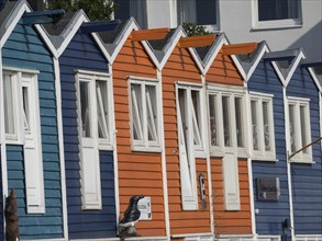 Rows of colourful house facades in blue, orange and turquoise on a clear day, bright sunshine,