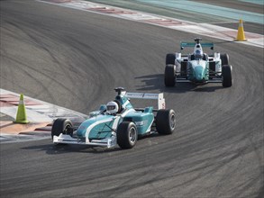 Two racing cars speed through a curve on the race track, tarmac under their wheels in competition,