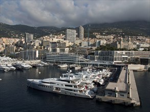 Marina in front of a city with a cloudy sky and surrounding mountains, monaco on the French