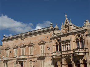A historic building with gothic windows and blue sky in the background, the town of mdina on the
