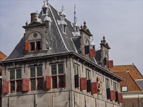 Historic building with red shutters, decorated roof and sculptures under a cloudy sky, historic