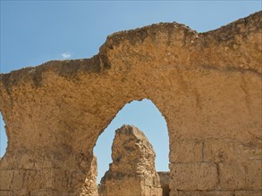 Ancient stone ruins with a large arch, blue sky in the background, Tunis in Africa with ruins from