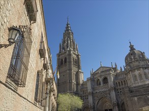 View of a gothic cathedral with a high tower and clear blue sky in the background, toledo, spain