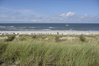 Idyllic beach landscape with dunes, sea, beach chairs and a ship on the horizon, Spiekeroog,