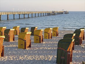 Beach chairs by a pier, illuminated by warm evening light, peaceful atmosphere, autumn atmosphere