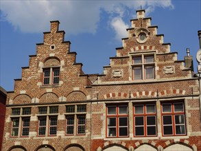 Brick architecture with magnificent stepped gables and windows silhouetted against a blue sky,