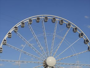 Close-up of a Ferris wheel in front of a clear blue sky, the beach of scheveningen with pier and