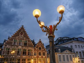 Street lamp in front of historic buildings in Bruges at night with clouds in the sky, historic