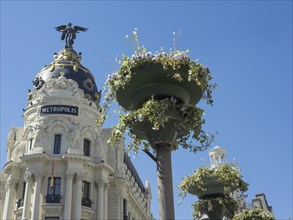 The Metropolis building with flowers in large planters under a clear sky, Madrid, Spain, Europe